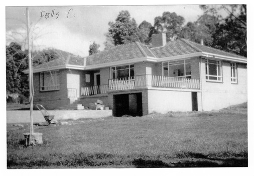 Shows a brick house with a garage underneath with lawn in front.