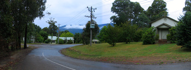 Shows a view looking down Barton Terrace in Marysville in Victoria. In the right of the photograph is a small weatherboard church. In the background are three buildings.