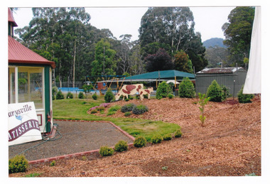 Shows the rotunda at the Marysville Patisserie in Marysville in Victoria. Shows a sign advertising the Patisserie. Shows the garden with a wooden cow and calf in the garden.