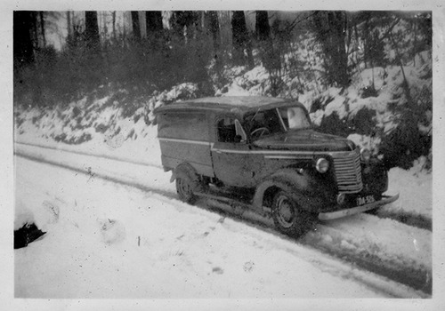 Shows delivery van driving down a snow covered track.