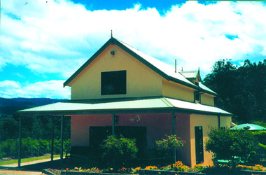 Shows a rendered two storey building surrounded by gardens. There is a verandah running along the front and left side of the building.