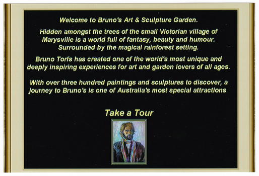 Shows a sign at the entrance to Bruno's Art & Sculptures Garden in Marysville in Victoria. Shows some information about the garden with a small copy of a painting of Bruno on the lower edge.