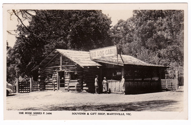 Shows the front facade of The Log Cabin in Marysville in Victoria. There are three ladies standing outside the building. On the reverse of the postcard is a space to write a message and an address and to place a postage stamp. The postcard is unused.