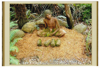 Shows a terracotta sculpture of a seated boy with a row of four pineapples laying in front of him on the ground. The boy is wearing a pair of dhoti trousers and is sitting cross-legged.