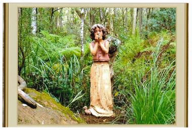 Shows a terracotta sculpture of a young girl standing with a duck at her feet. The girl is wearing a vest like top and a long skirt and has shoulder length hair. She is holding her hands to her mouth.