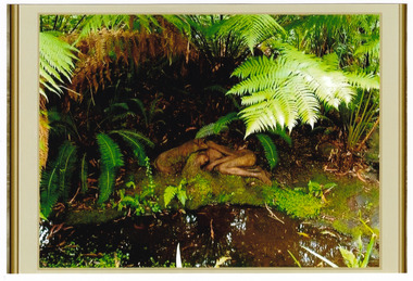 Shows a terracotta sculpture of a naked woman lying under a tree fern next to a small pond. Lying with the woman is a pig.