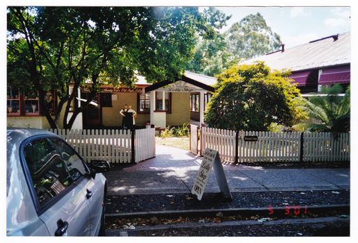 Shows the front fence and arbor of Uncle Fred & Aunty Val's Old Style Lolly Shop in Marysville in Victoria. Shows a wooden fence with a gateway leading through to the shop entrance.