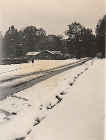 Shows The Log Cabin in Marysville in Victoria covered and surrounded by a heavy snowfall.