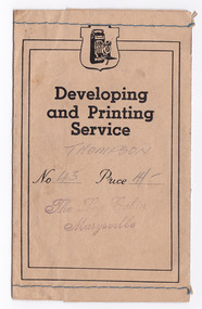 Shows an envelope that was used to present photographs or negatives after they were developed and printed. Envelope has blue stitching along both upper and lower edges.