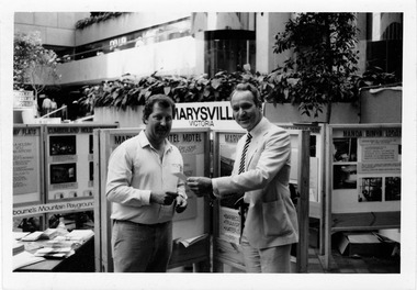 Shows Colin Wood from The Cumberland in Marysville speaking to Brian Milnes, the Marketing Manager for Victour at the Holiday and Leisure Show during an unknown year.