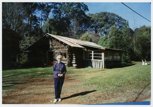 Shows a lady standing out the front of The Log Cabin in Marysville in Victoria.