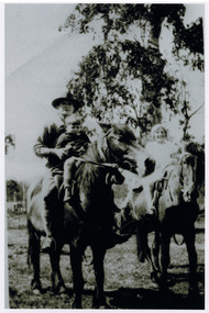 Shows members of the Branchflower family in Marysville in Victoria. Shows a man seated with a small boy in front of him on a horse. Shows another horse with a young girl riding it.