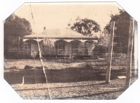 Shows a weatherboard farmhouse with a verandah running along the front.