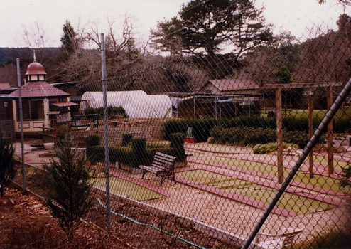 Shows some of the holes of the mini golf course at Magic Creek Nursery in Marysville in Victoria. In the background is a gazebo. 