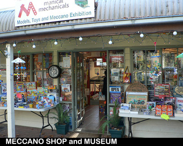 Shows the shop front of Manical Mechanicals in Marysville in Victoria. Out the front of the shop are two fold out tables covered with various toys and games for sale.