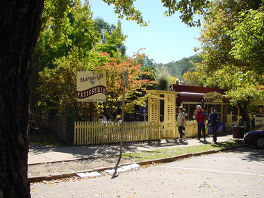 Shows the front entrance, garden and front facade of the Marysville Patisserie in Marysville in Victoria.