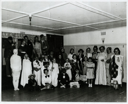 A copy of a black and white photograph of an unknown group of people at a fancy dress ball at The Marysville Chalet. The original photograph was taken in 1954.