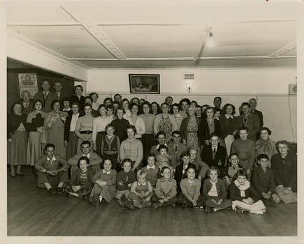 A black and white photograph of Elsie Ackerman, proprietress of The Marysville Chalet, with a group of local residents at The Marysville Chalet in May 1954.