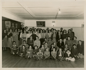 A black and white photograph of Elsie Ackerman, proprietress of The Marysville Chalet, with a group of local residents at The Marysville Chalet in May 1954.