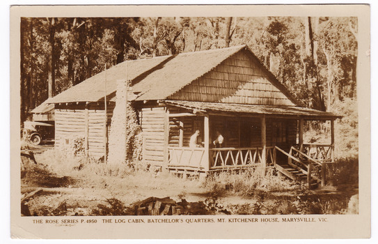 A sepia postcard of the log cabin batchelor's quarters at Mt. Kitchener House in Marysville that was produced by the Rose Stereograph Company as a souvenir of Marysville. On the reverse of the postcard is a space to write a message and and address to place a postage stamp. The postcard is unused.