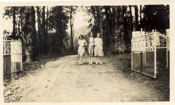 A digital copy of a black and white photograph of three young women standing at the entrance gates to Mount Kitchener House in Marysville that was taken in 1930.