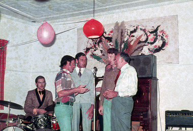 A digital copy of a colour photograph of a group of five men entertaining the crowd at a function at Mountain Lodge in Marysville that was taken in 1972.