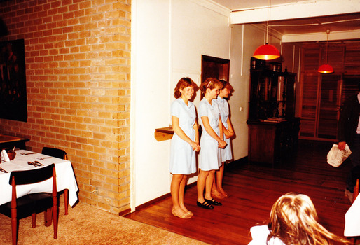 A digital copy of a colour photograph of an unknown group of three young women taken in the interieor of Mountain Lodge in 1985.