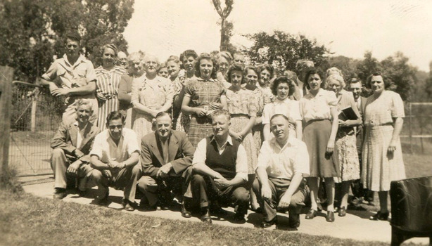 A digital copy of a black and white photograph of Pat and Ewen Cumming with a large group of unknown people at Roseleigh Guest House in Marysville. The original photograph was taken in 1945.