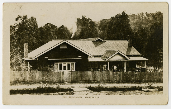 A black and white photograph of The Bungalow in Marysville. The Bungalow was built in 1917 by the Cuzens Bros. Builders for Frederick and Vera Barton. The postcard was produced by the Rose Stereographs as a souvenir of Marysville. On the reverse of the postcard is a space to write a message and an address and to place a postage stamp. The postcard is unused.