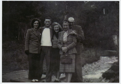 A copy of a black and white photograph of an unknown group of guests staying at Kooringa Guest House in Marysville standing by a river. The original photograph was taken in 1947.