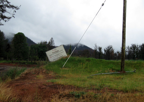 A digital copy of a colour photograph that was taken of the sign that stood at the front entry to Kooringa Resort and Conference Centre. The original photograph was taken in late 2009, after the Black Saturday bushfires of February 2009 destroyed the resort and the majority of the town of Marysville.