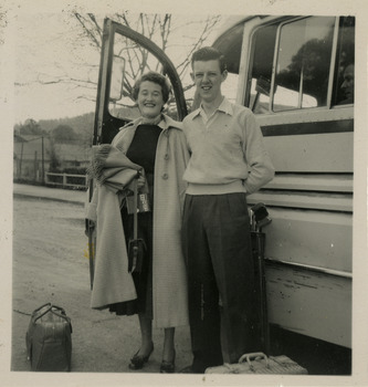 A black and white photograph of guests staying at Mary-Lyn Guest House in Marysville. Mary-Lyn was a part of the Mary Chain of guest houses built by Eric Dowdle in the Depression years. The photograph shows a lady and a man with their luggage, standing next to a bus.