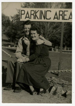A black and white photograph taken at Mary-Lyn Guest House in Marysville. Mary-Lyn was a part of the Mary Chain of guest houses built by Eric Dowdle in the Depression years. The photograph was taken in 1954 and is of Warren Titcher and Marg Martin sitting in the car park at Mary-Lyn.