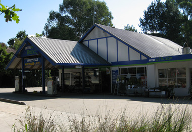 Shows the front facade of the Marysville Hardware and Auto in Marysville in Victoria. Shows the front of the building with two petrol bowsers out the front.