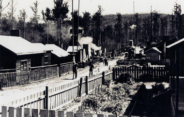 A copy of a black and white photograph of Cambarville township near Marysville.  Cambarville was established as a timber mill town in the 1940s. Timber mill owners A. Cameron and F.J. Barton named Cambarville. They established the mill to salvage timber from trees destroyed in the 1939 bushfires. Cambarville was impacted by the 2009 Black Saturday bushfires and any remaining structures were destroyed. 