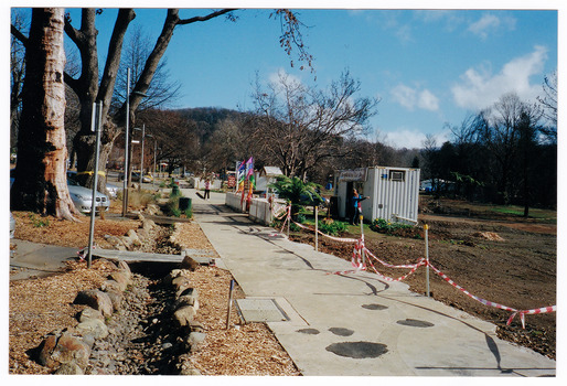 Shows the temporary premises of the Marysville Old Style Lolly Shop in Victoria. Shows a shipping container which is situated behind an old picket fence and is surrounded by bare earth.