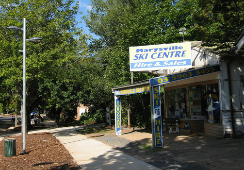 Shows the front facade of the Marysville Ski Centre in Victoria. Shows a building with advertising signs attached to the roof and verandah.