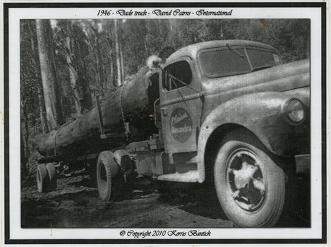 A black and white photograph of David Cairns International truck hauling logs on a timber jinker.