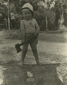 Two black and white photographs of Lloyd Gould in his younger years. In the photographs he is standing on a log weilding a tomohawk to chop the log.