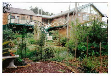 Shows a photograph of the rear of the main building and garden at Arbor Green Galleries in Marysville. Shows a large building with verandahs and stairs leading down to the garden.