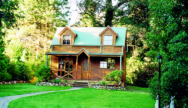 Shows a photograph of Ashlar Cottage B&B in Marysville. Shows a timber two storey building with a verandah at the front. The building is backed by a large garden.