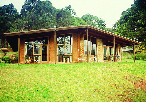 Shows a colour photograph of one of the Barree Mud Brick Holiday Cottages in Marysville. Shows a mud brick building with a verandah along the front facade.