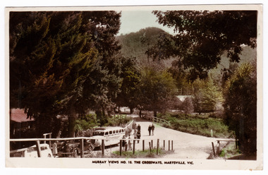 A colour tinted postcard of the Crossways in Marysville in Victoria. On the reverse is a space to write a message and an address and to place a postage stamp. The postcard is unused.