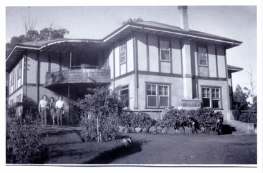 A black and white photograph taken at Mary Lodge Guest House in Marysville. The photograph was taken of three unknown people standing out the front of Mary Lodge. The photograph was taken in April 1944.