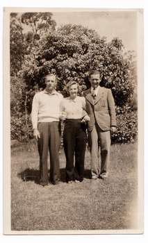 A black and white photograph taken in the garden at Mary Lodge Guest House in Marysville. The photograph is of an unknown group of three people. The photograph was taken in 1941.