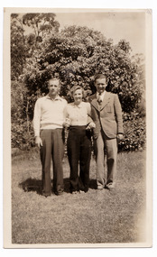 A black and white photograph taken in the garden at Mary Lodge Guest House in Marysville. The photograph is of an unknown group of three people. The photograph was taken in 1941.