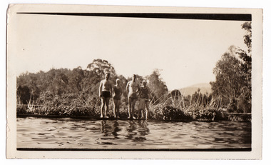 A black and white photograph taken at Mary Lodge Guest House in Marysville. The photograph is of a group of four unknown adults and a child standing on the edge of the swimming pool at Mary Lodge. The photograph was taken in 1941.