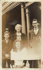 A digital copy of a black and white photograph of the Chester Family standing on a verandah of unknown building.
