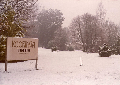 A sepia copy of a photograph taken at Kooringa Tourist House in Marysville. The photograph is of the front entrance sign with the main house in the background and was taken during winter.