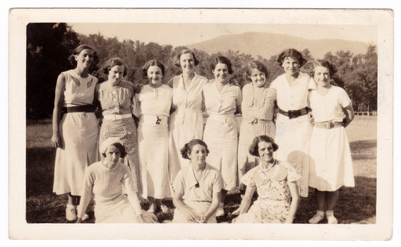 A black and white photograph taken of a ladies cricket team who were staying at Mary-Lyn Guest House in Marysville. Mary-Lyn was part of the Mary Chain of guest houses built by Eric Dowdle in the Depression years. The photograph shows the group of eleven ladies at an unknown location.